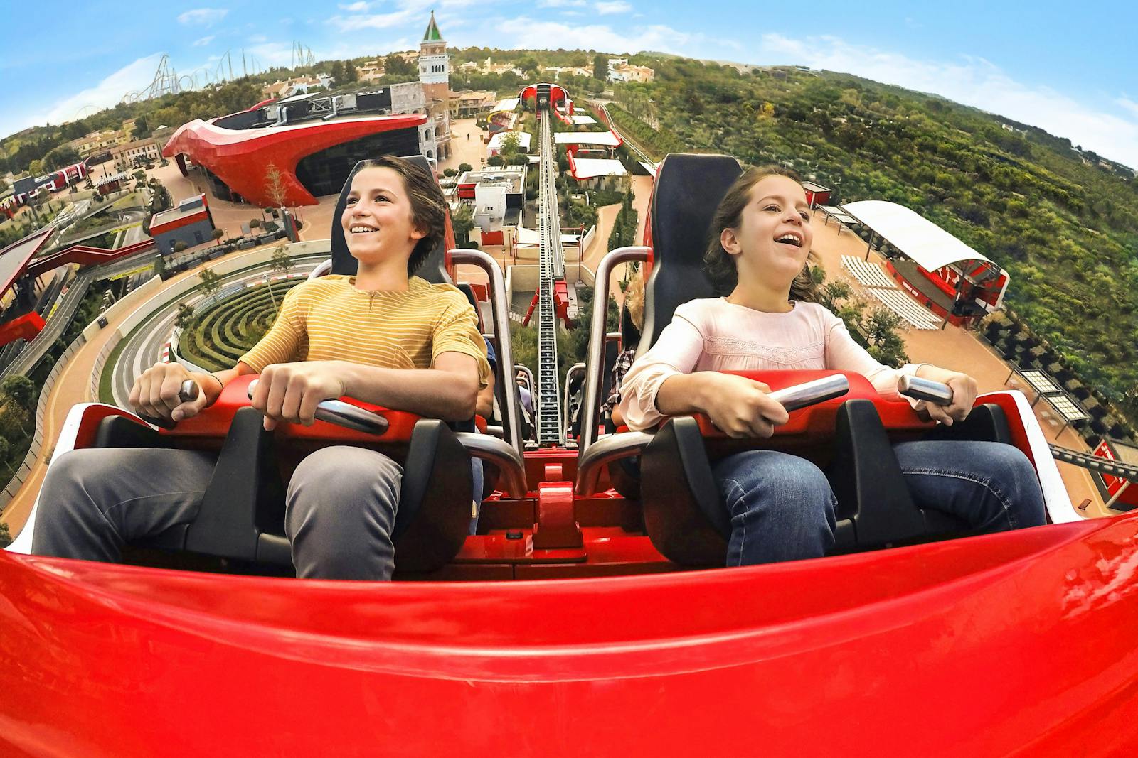 Two smiling children on a roller coaster at PortAventura World